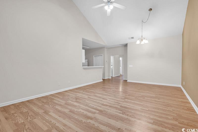 4672 Lightkeepers Way, Unit 50E Little River, SC 29566 - Photo 4 of 19 Unfurnished living room featuring ceiling fan with notable chandelier, light wood-type flooring, and high vaulted ceiling