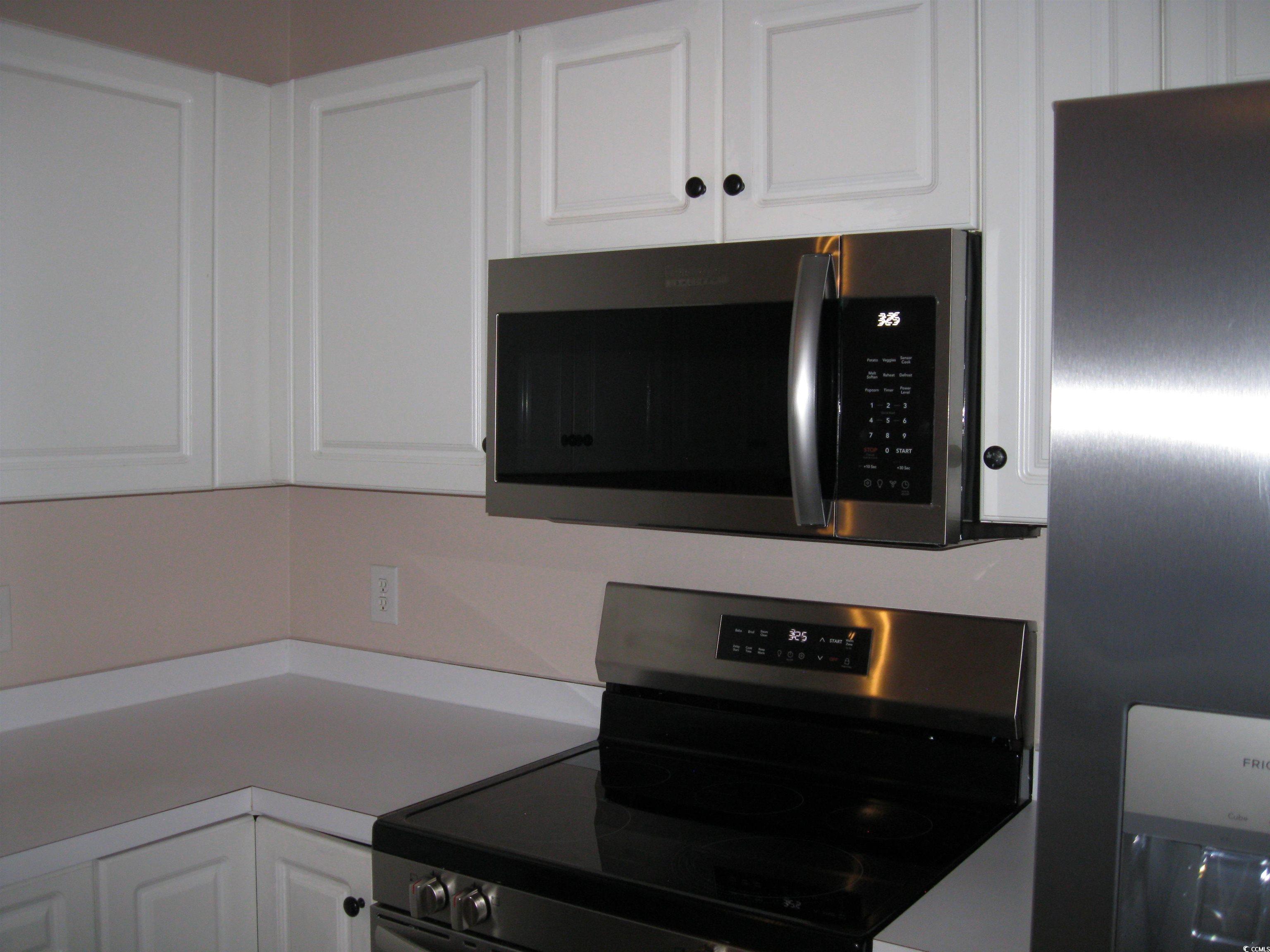 4672 Lightkeepers Way, Unit 50E Little River, SC 29566 - Photo 5 of 19 Kitchen with white cabinetry, stainless steel appliances, and light countertops
