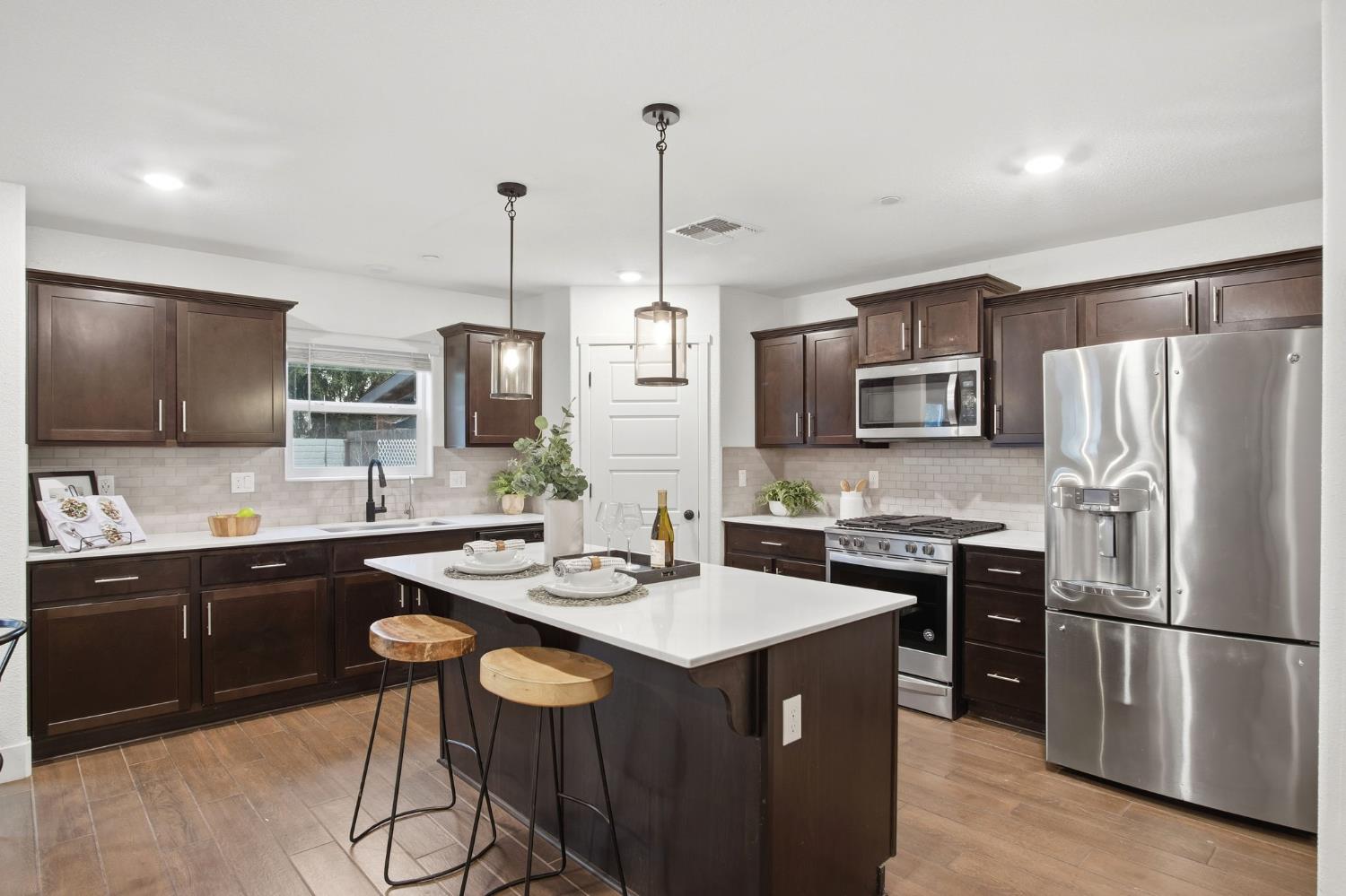 1666 Oak Street Los Banos, CA 93635 - Photo 5 of 34 a kitchen with stainless steel appliances a stove a sink a refrigerator a center island and chairs