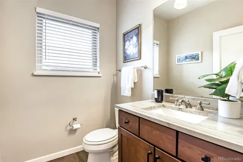 a bathroom with a granite countertop sink toilet and a window