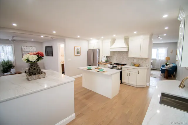 a kitchen with stainless steel appliances kitchen island granite countertop a sink and white cabinets
