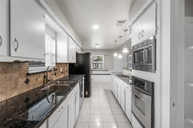 a large kitchen with stainless steel appliances granite countertop a sink and cabinets