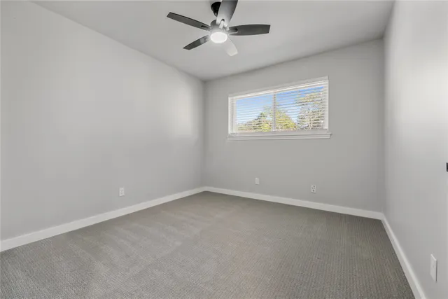 an empty room with a window and a fan