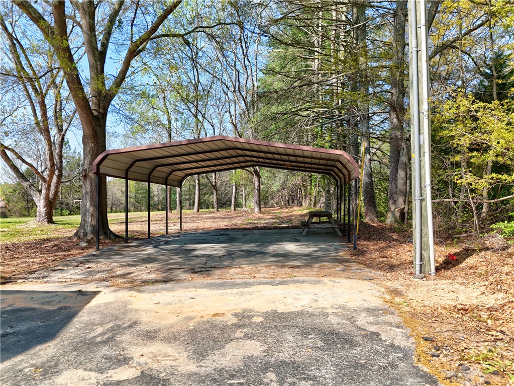 220 Bill Kay Road Belton, SC 29627 - Photo 26 of 30 This spacious carport offers practical outdoor shelter amidst a natural, wooded setting.
