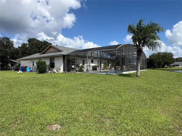 a view of house with a big yard and potted plants