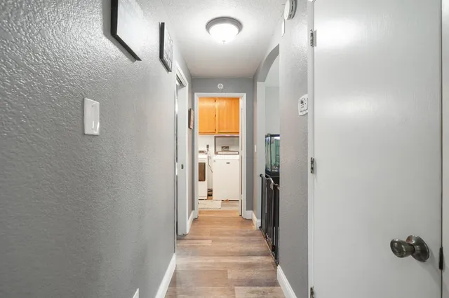 a view of a hallway with wooden floor and a bathroom