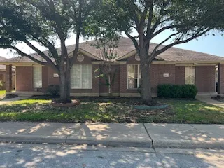 a large tree in front of a brick house