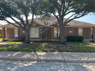 a large tree in front of a brick house