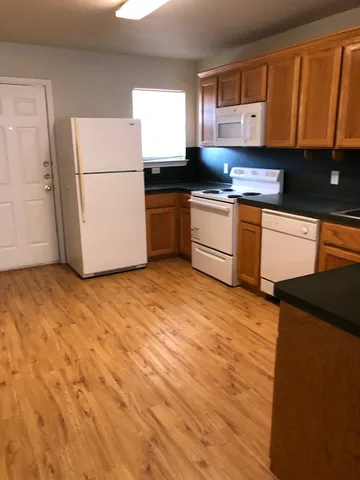 a kitchen with granite countertop a refrigerator a sink and white cabinets