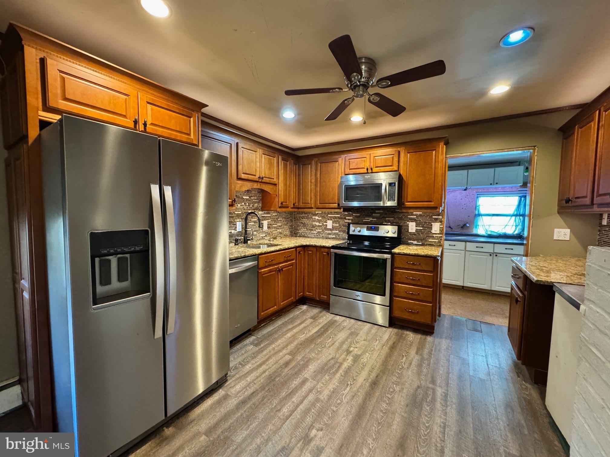 31 Swan Lane Levittown, PA 19055 - Photo 5 of 17 a kitchen with stainless steel appliances granite countertop a refrigerator a sink dishwasher a stove and a refrigerator with wooden floor