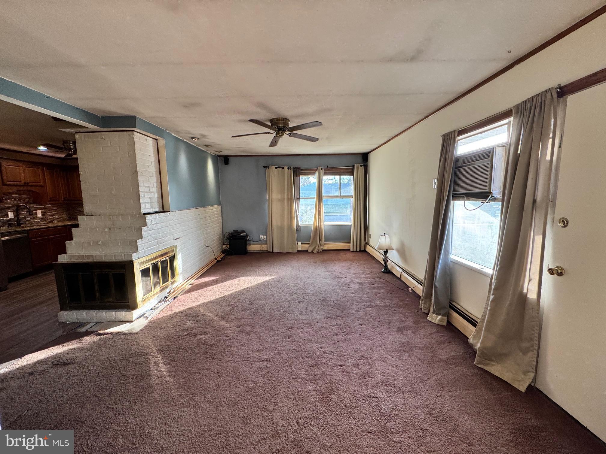 31 Swan Lane Levittown, PA 19055 - Photo 8 of 17 a view of a livingroom with a fireplace a ceiling fan and windows