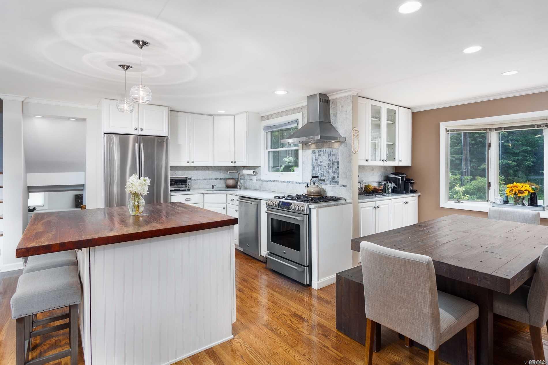 19 Nursery Road Melville, NY 11747 - Photo 1 of 1 a kitchen with kitchen island a stove a sink a refrigerator and a dining table with wooden floor