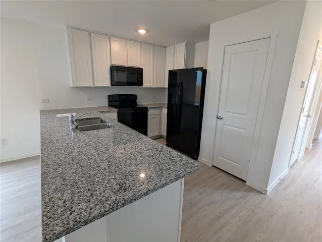 a kitchen with granite countertop a refrigerator and a sink