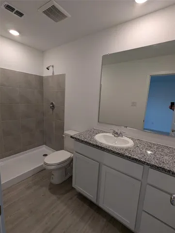 a bathroom with a granite countertop sink a toilet a mirror and bathtub