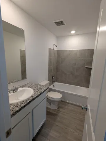 a bathroom with a granite countertop sink a toilet a mirror and shower