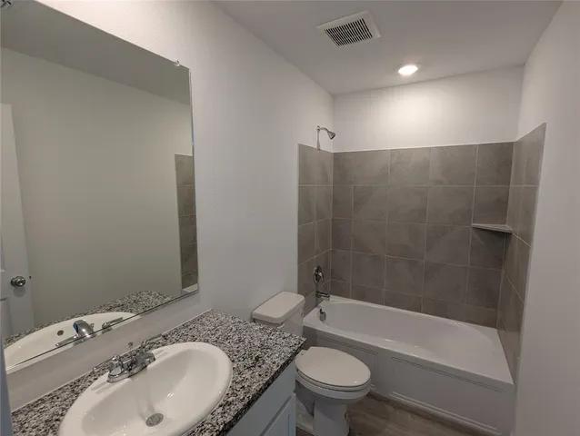 a bathroom with a granite countertop sink a toilet and bathtub