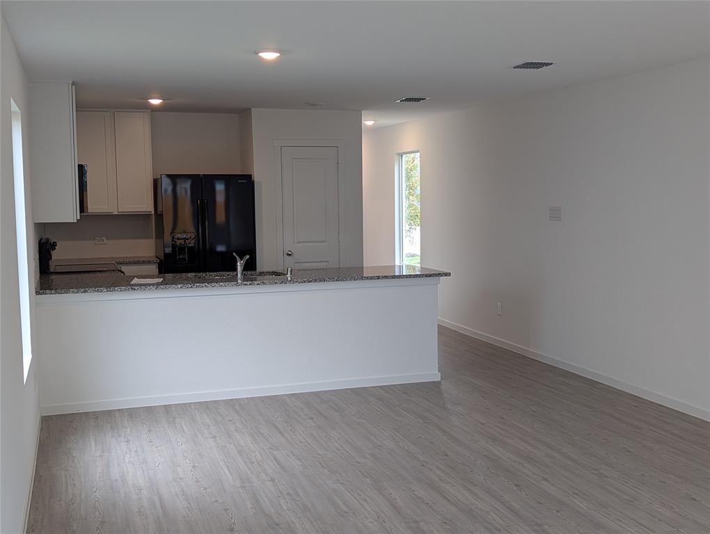 904 Wood Stork Way Princeton, TX 75407 - Photo 10 of 40 an empty room with wooden floor and windows