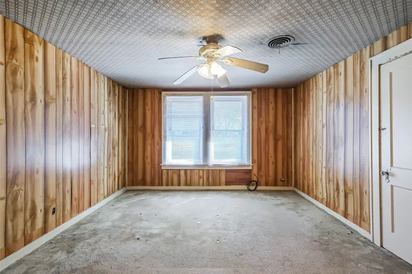 an empty room with windows and chandelier fan
