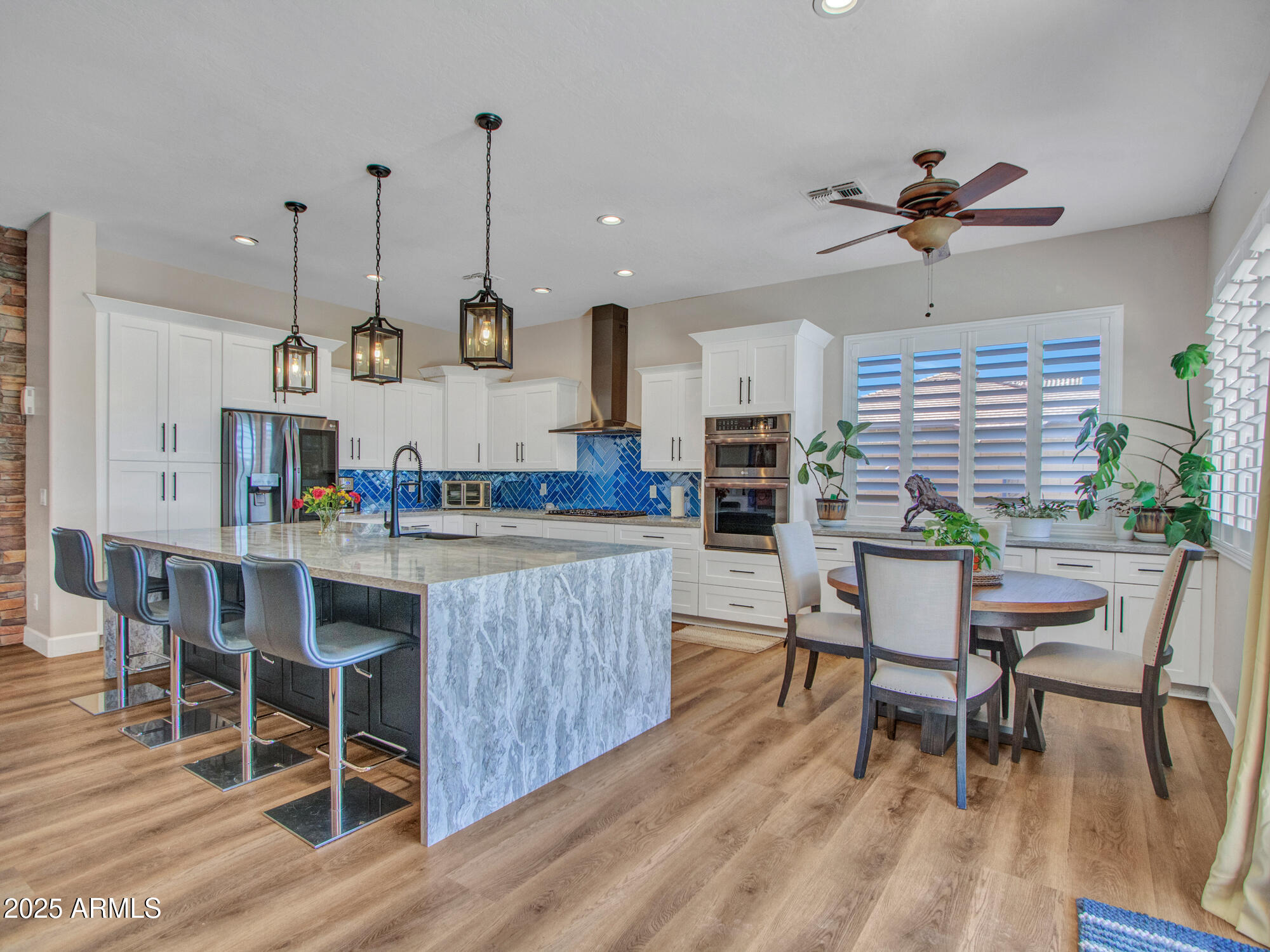 6919 West Rowel Road Peoria, AZ 85383 - Photo 18 of 74 a kitchen with stainless steel appliances granite countertop a kitchen island a stove a table and chairs in it