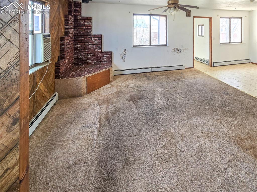 722 6th Street Hugo, CO 80821 - Photo 11 of 35 Unfurnished living room featuring baseboard heating, a ceiling fan, and carpet floors