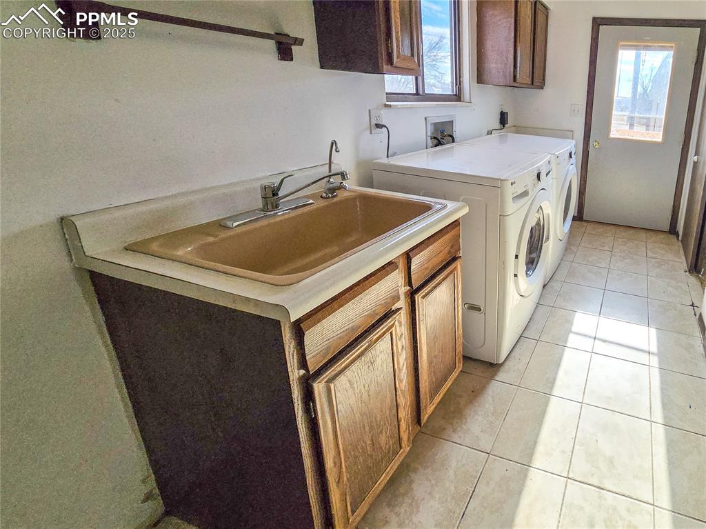 722 6th Street Hugo, CO 80821 - Photo 18 of 35 Clothes washing area featuring cabinet space, washing machine and dryer, light tile patterned flooring, and a sink