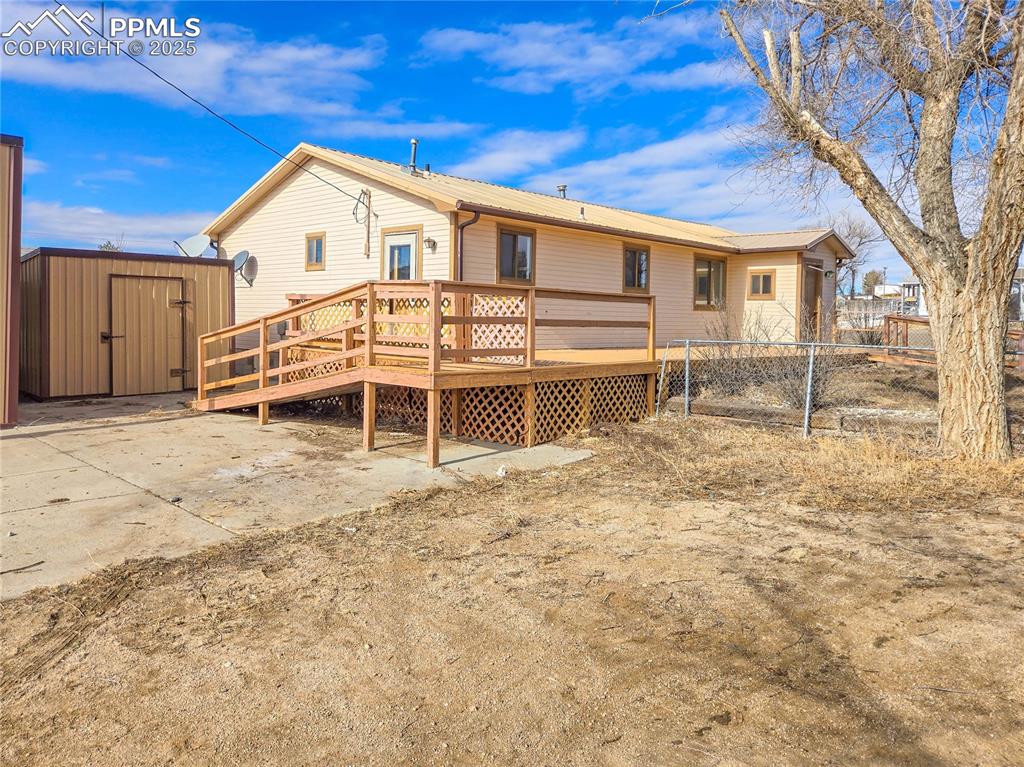 722 6th Street Hugo, CO 80821 - Photo 3 of 35 Back of property with a wooden deck, an outbuilding, metal roof, fence, and a storage unit