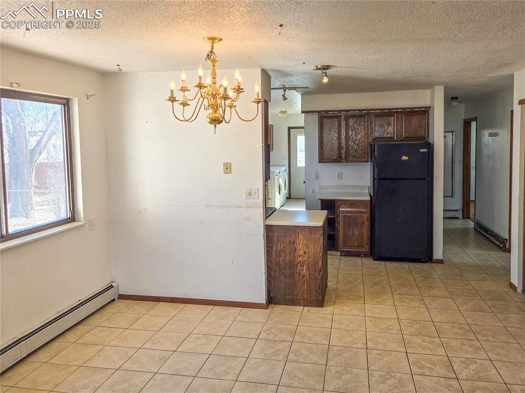 722 6th Street Hugo, CO 80821 - Photo 31 of 35 Kitchen featuring freestanding refrigerator, a chandelier, a baseboard heating unit, light countertops, and light tile patterned flooring