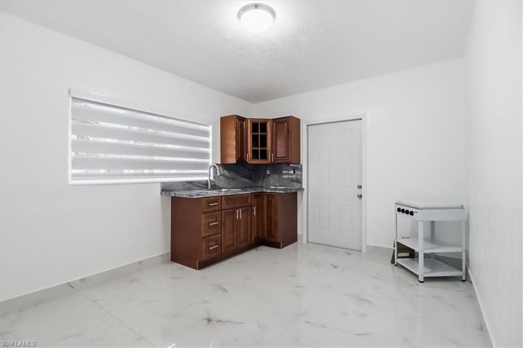 6800 Northwest 28th Avenue Miami, FL 33147 - Photo 19 of 40 Kitchen featuring light marble finish flooring, glass insert cabinets, tasteful backsplash, and dark stone counters