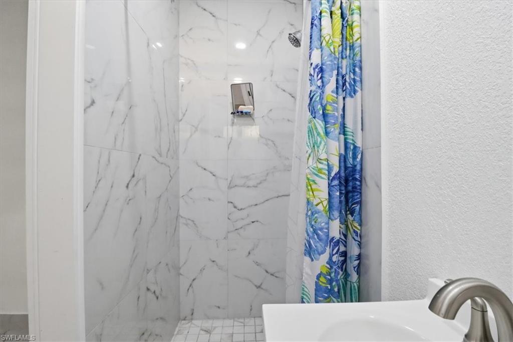 6800 Northwest 28th Avenue Miami, FL 33147 - Photo 20 of 40 Full bathroom with a marble finish shower, a textured wall, and vanity