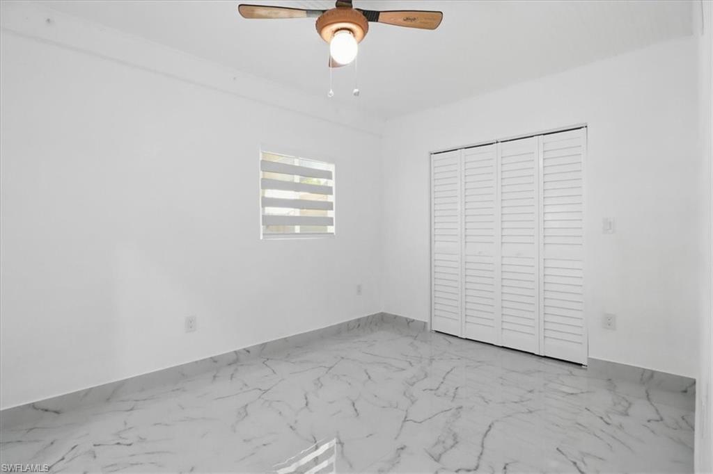 6800 Northwest 28th Avenue Miami, FL 33147 - Photo 26 of 40 Unfurnished bedroom with marble look tiles, a closet, and a ceiling fan
