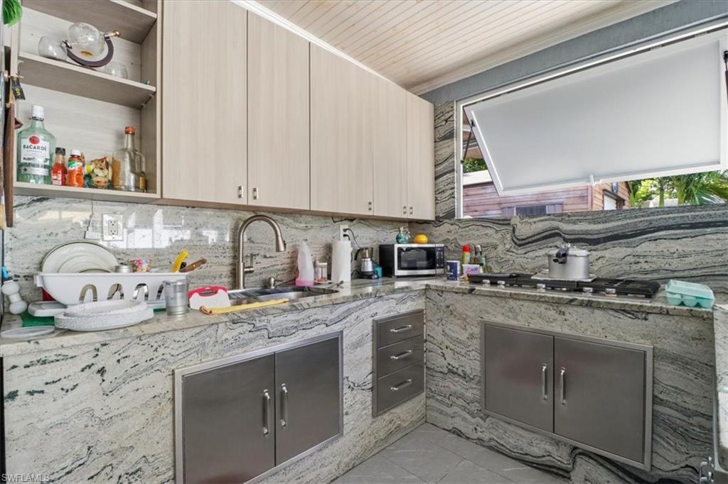 6800 Northwest 28th Avenue Miami, FL 33147 - Photo 32 of 40 Kitchen featuring open shelves, light stone countertops, appliances with stainless steel finishes, and tasteful backsplash