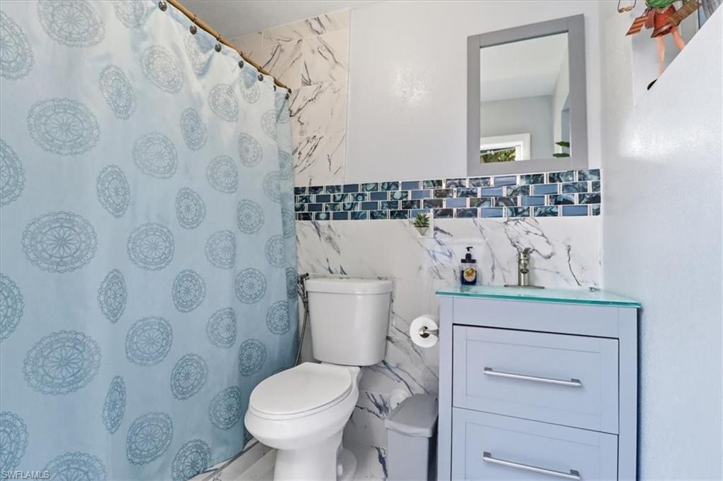 6800 Northwest 28th Avenue Miami, FL 33147 - Photo 33 of 40 Full bathroom with vanity, a shower with shower curtain, and tile walls