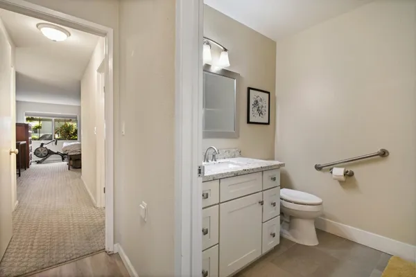 a bathroom with a granite countertop toilet a sink and a mirror