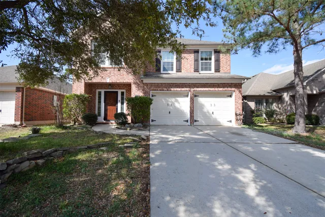 a view of a white house with a yard plants and large tree