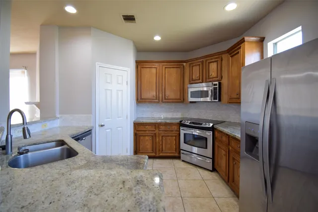 a kitchen with stainless steel appliances granite countertop a refrigerator and a stove top oven
