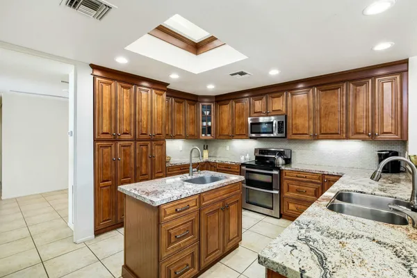 a kitchen with granite countertop stainless steel appliances a stove sink and microwave