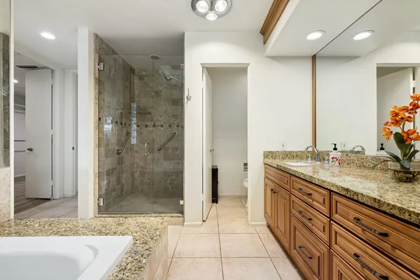 a bathroom with a granite countertop sink a mirror and shower