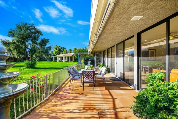 a view of a patio with table and chairs potted plants with wooden floor and fence