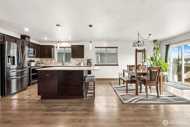 a living room with stainless steel appliances furniture and a kitchen view