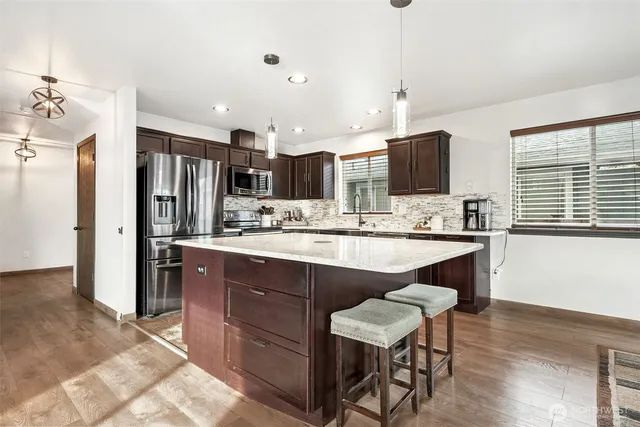 a kitchen with stainless steel appliances granite countertop a sink refrigerator and cabinets