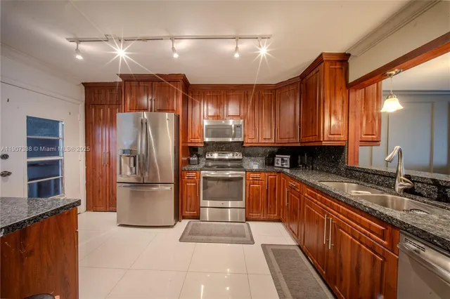a kitchen with stainless steel appliances granite countertop a refrigerator and a sink