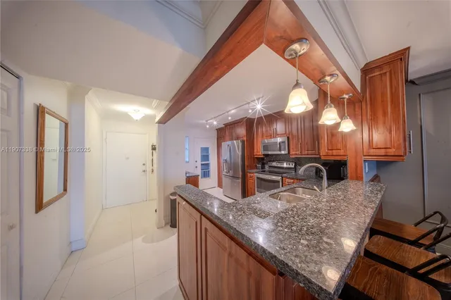 a kitchen with granite countertop kitchen island stainless steel appliances refrigerator sink and cabinets