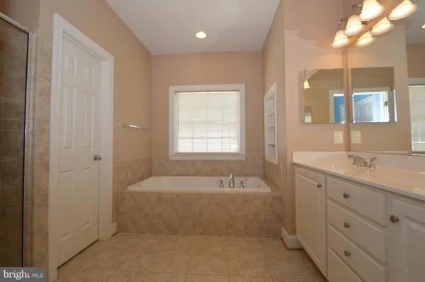 a spacious bathroom with a tub sink and mirror