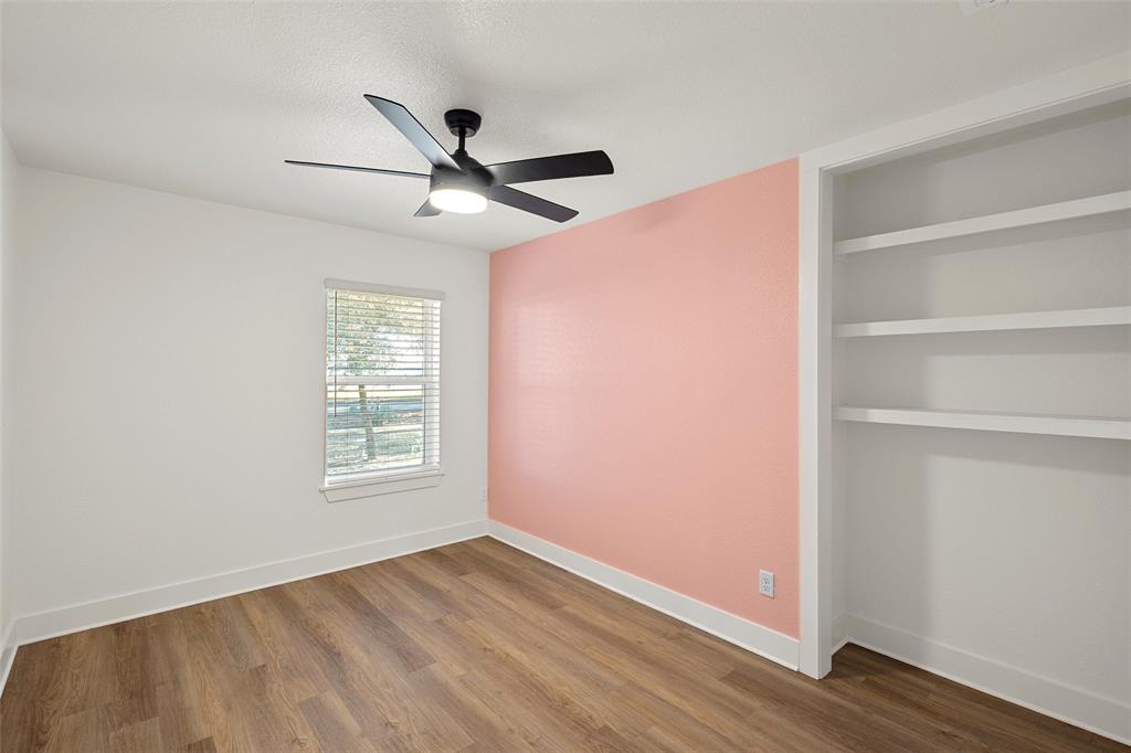 175 4 Corners Road West, TX 76691 - Photo 22 of 30 an empty room with wooden floor a ceiling fan and windows