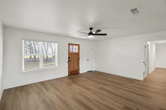 a view of an empty room with a window and wooden floor