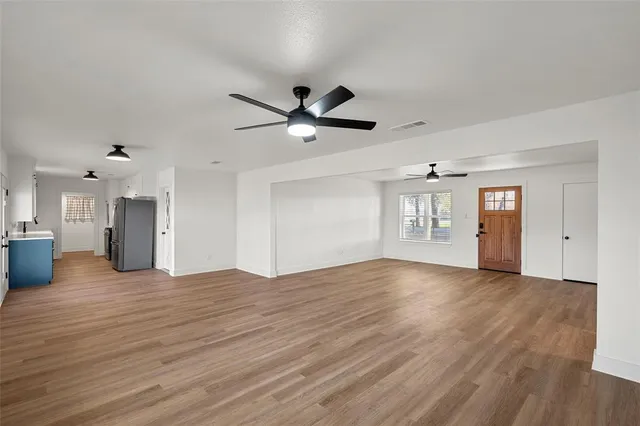 a view of an empty room with window and wooden floor