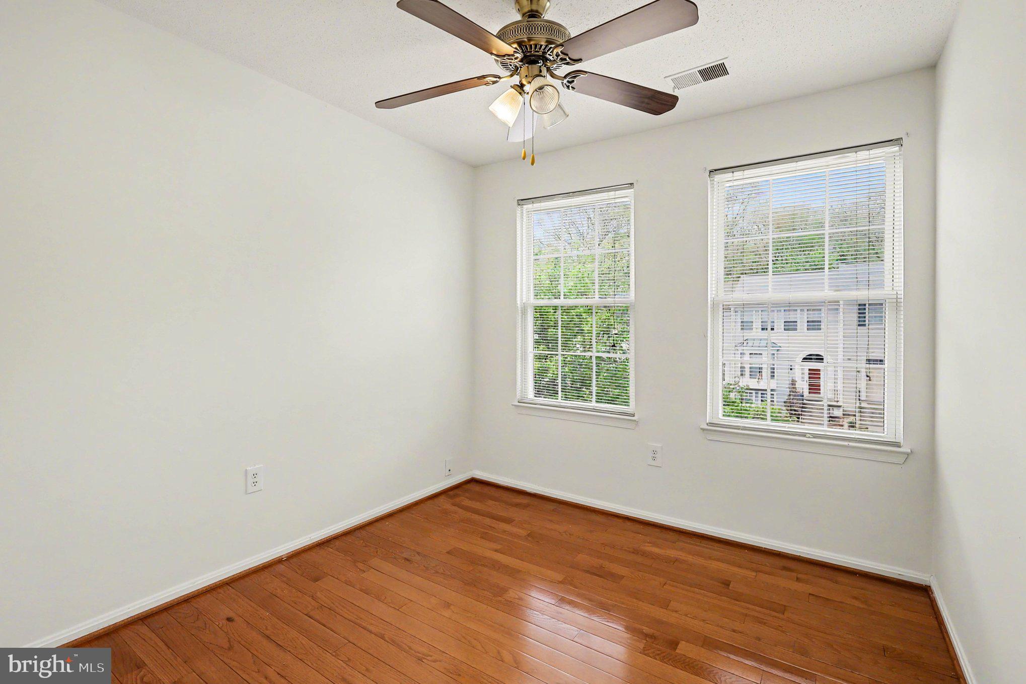 14721 McKnew Road Burtonsville, MD 20866 - Photo 9 of 30 an empty room with wooden floor chandelier fan and windows