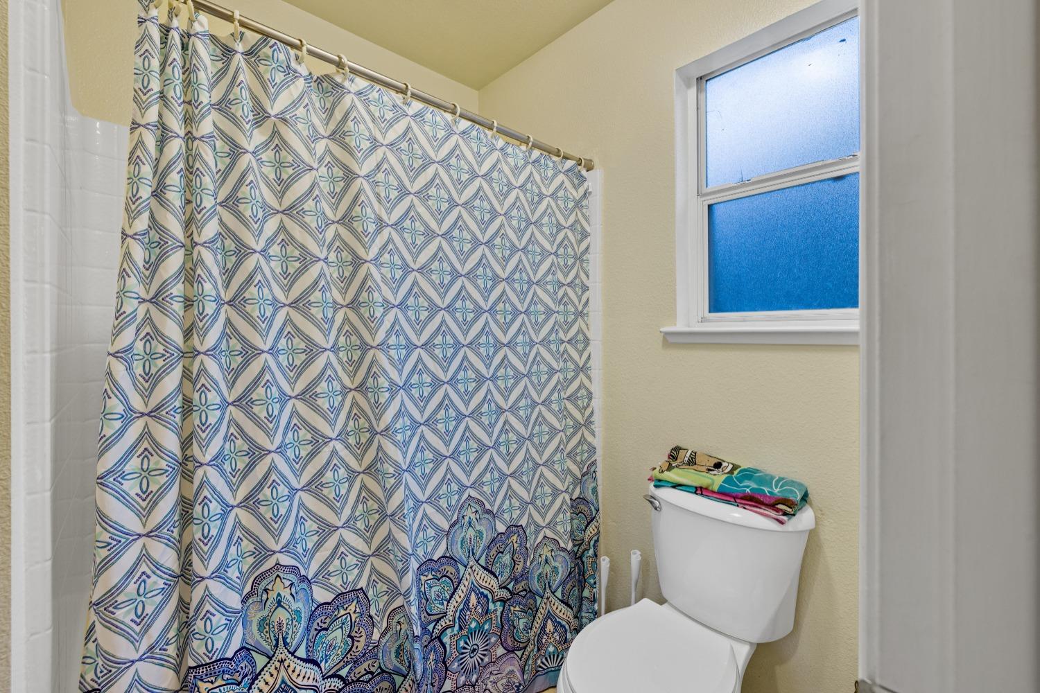 13590 9th Street Parlier, CA 93648 - Photo 17 of 30 a white toilet sitting next to a shower curtain