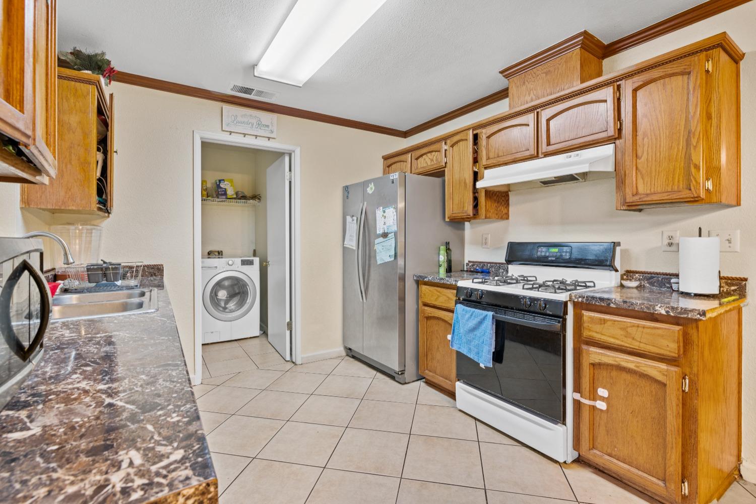 13590 9th Street Parlier, CA 93648 - Photo 10 of 30 a kitchen with stainless steel appliances granite countertop a stove a washer and dryer