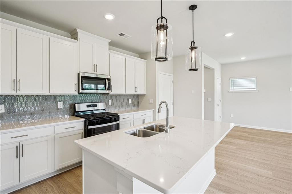2034 Avalon Ridge Conyers, GA 30013 - Photo 11 of 35 a kitchen with kitchen island a white counter top space cabinets and stainless steel appliances